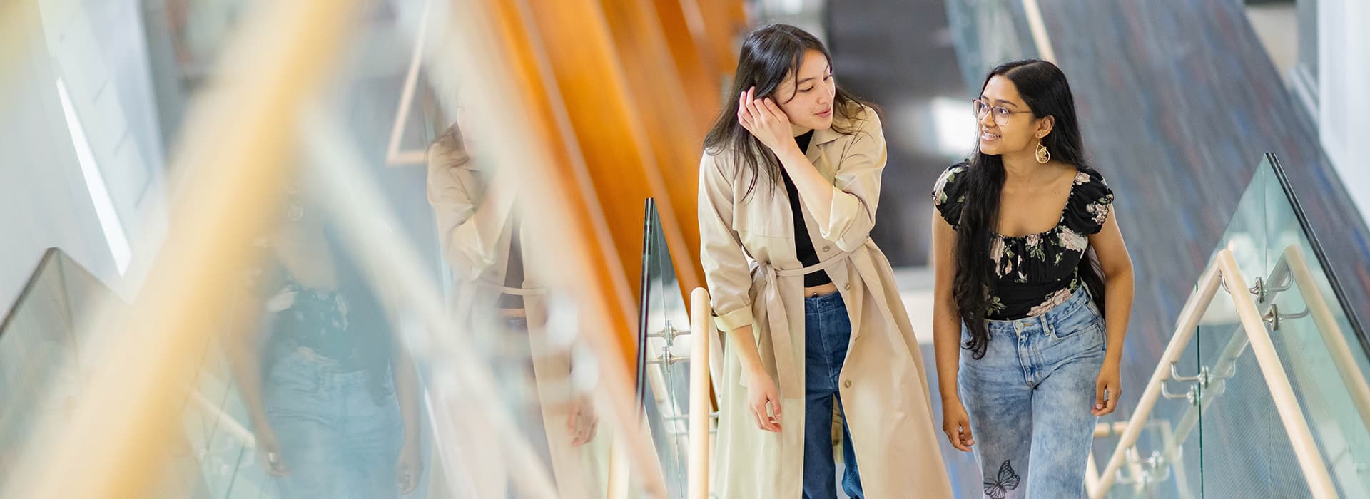 Two female students talking while walking up a flight of stairs