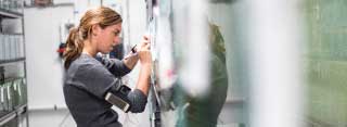 A young woman writes a notice on the wall of a research lab.