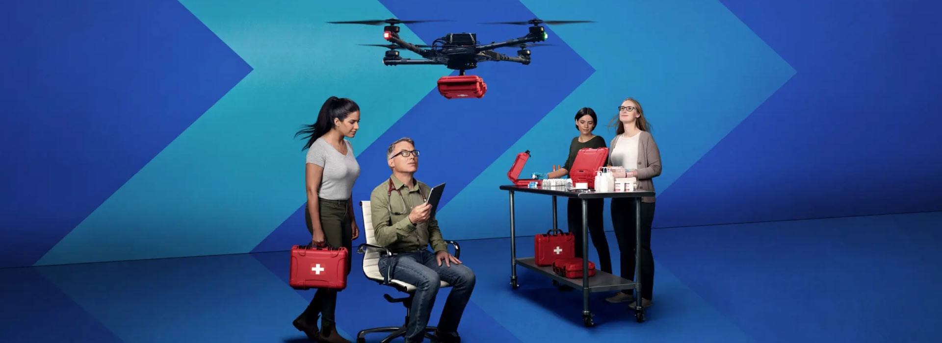 Four people in a lab test a drone that carries a medical box and supplies