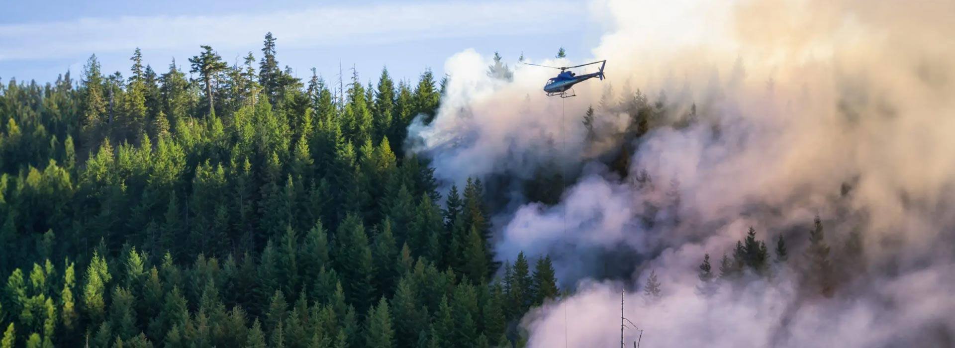 Helicopter fighting British Columbia wildfires on a hot sunny summer day.