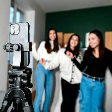 Three people standing infront of a phone on a tripod