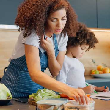 A mother meal prepping in a kitchen beside her child