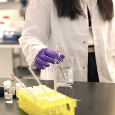 Researcher in a lab testing the stir stick in a clear solution