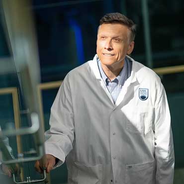 Dr. Erik Pioro standing on a stairwell beside his reflection in a lab coat