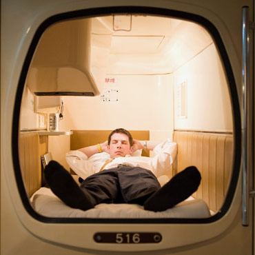 A person lying down asleep, in a sleeping pod