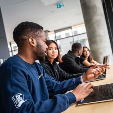 Students sitting at a window on their laptops