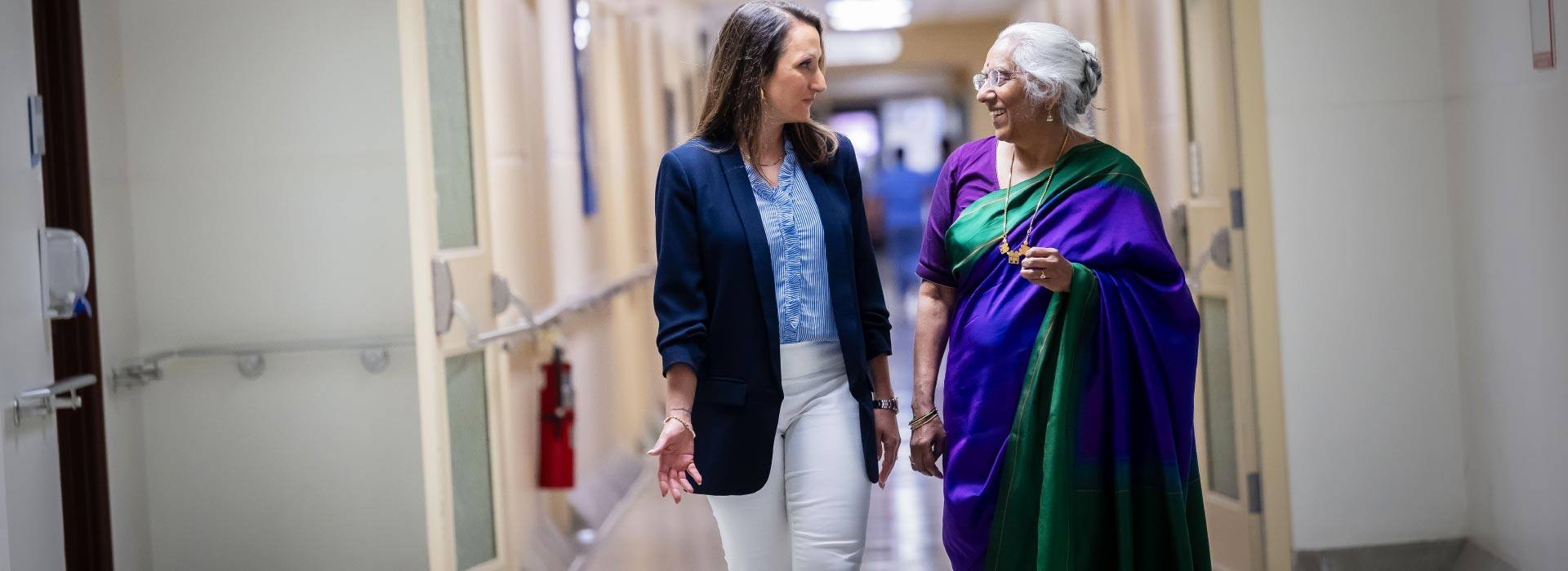 UBC Professors Dr. Lori Brotto and Dr. Saraswathi Vedam walking down a hospital hallway.