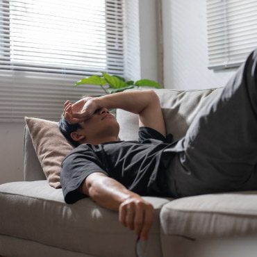 Man looking stressed while laying on a sofa