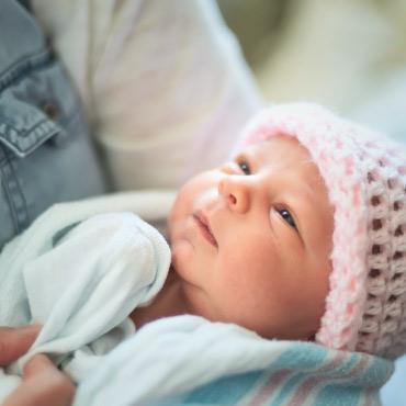 newborn baby in the arms of an adult