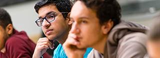 Two students in a classroom paying close attention to the presenter