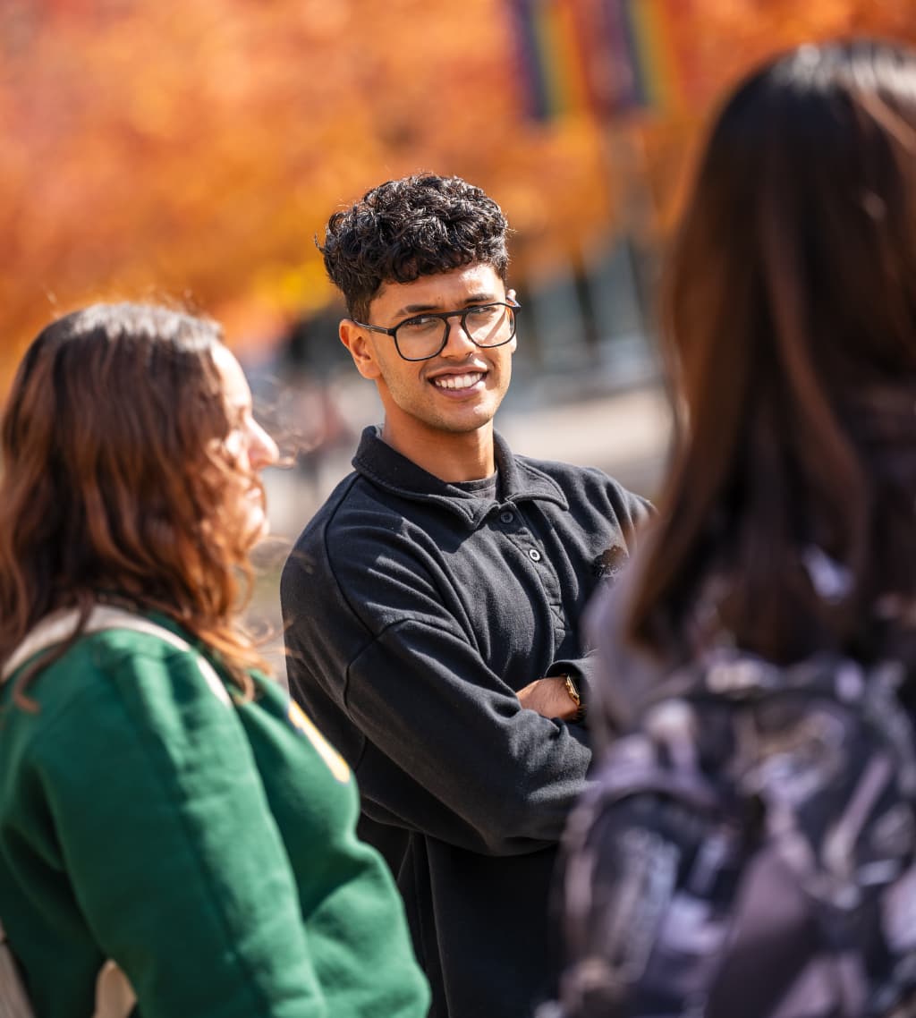 Two students walk and talk on UBC Vancouver campus during the fall