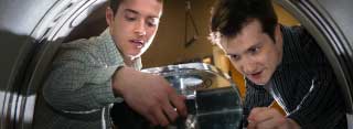 Two young men lift a glass lid on a research project.