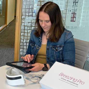 A woman at a table on a tablet, with the new testing device beside her